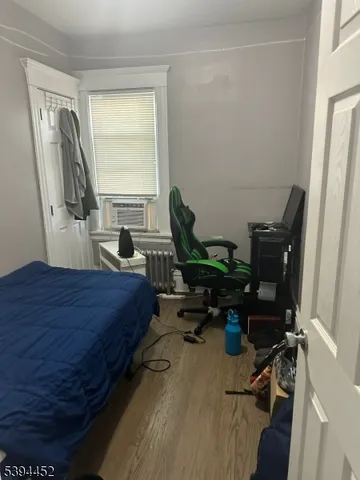 a bedroom with a bed a large window and wooden floor