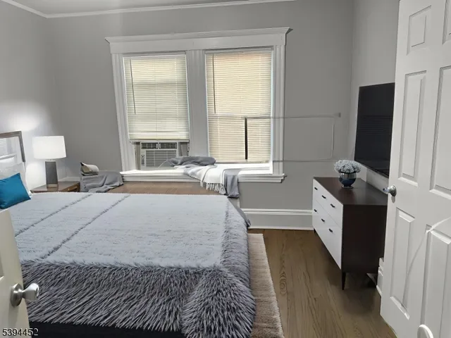 a bedroom with a bed wooden floor and a large window