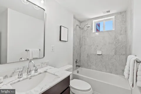 a bathroom with a granite countertop sink toilet and shower