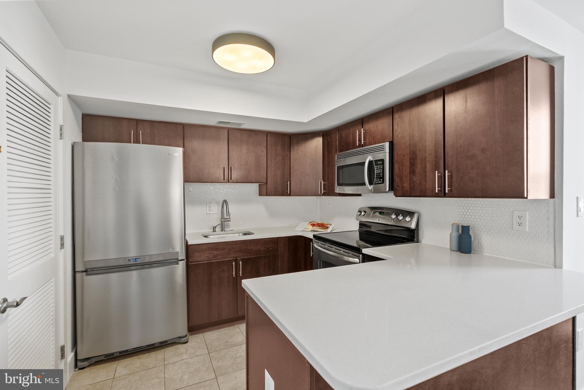 1461 Girard Street Northwest, Unit 201 Washington, DC 20009 - Photo 9 of 24 a kitchen with stainless steel appliances a refrigerator stove microwave and sink