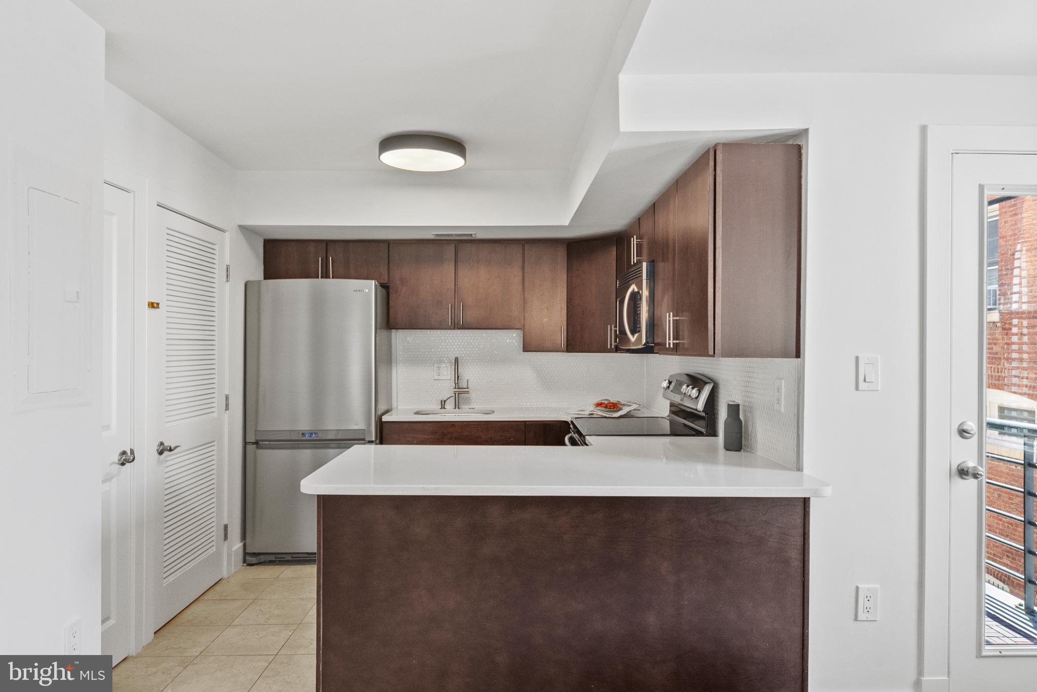 1461 Girard Street Northwest, Unit 201 Washington, DC 20009 - Photo 10 of 24 a kitchen with stainless steel appliances a sink stove and refrigerator
