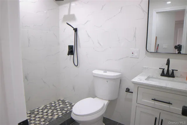 a bathroom with a granite countertop toilet sink and mirror