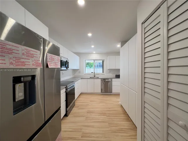 a kitchen with granite countertop white cabinets appliances a sink and a window