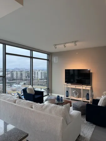 a living room with furniture a flat screen tv and a floor to ceiling window