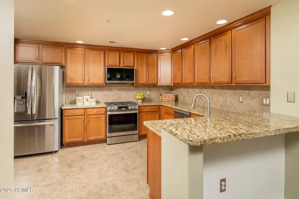 a kitchen with stainless steel appliances granite countertop a stove a sink dishwasher a refrigerator and cabinets with wooden floor