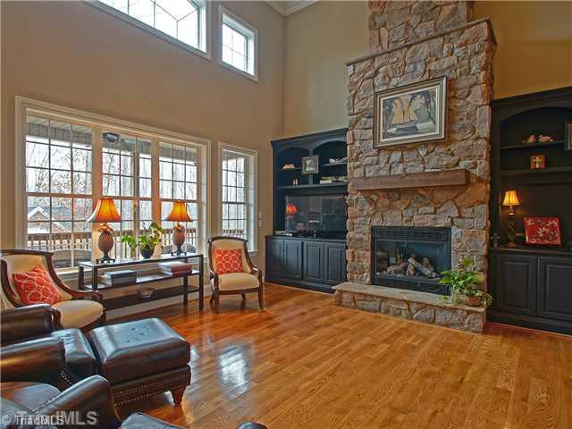 8500 Crested Oak Court Oak Ridge, NC 27310 - Photo 4 of 16 Den/Family/Great Room. In the great room, a massive stone fireplace is flanked by equally dominant built-ins. A wall of windows floods the room with natural light and the honey-stained hardwoods anchor everything bringing cozy warmth to the room.