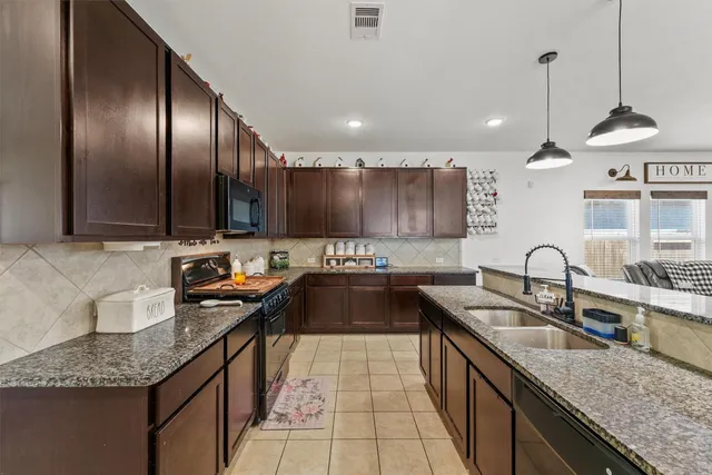 a kitchen with granite countertop stainless steel appliances a sink stove and cabinets