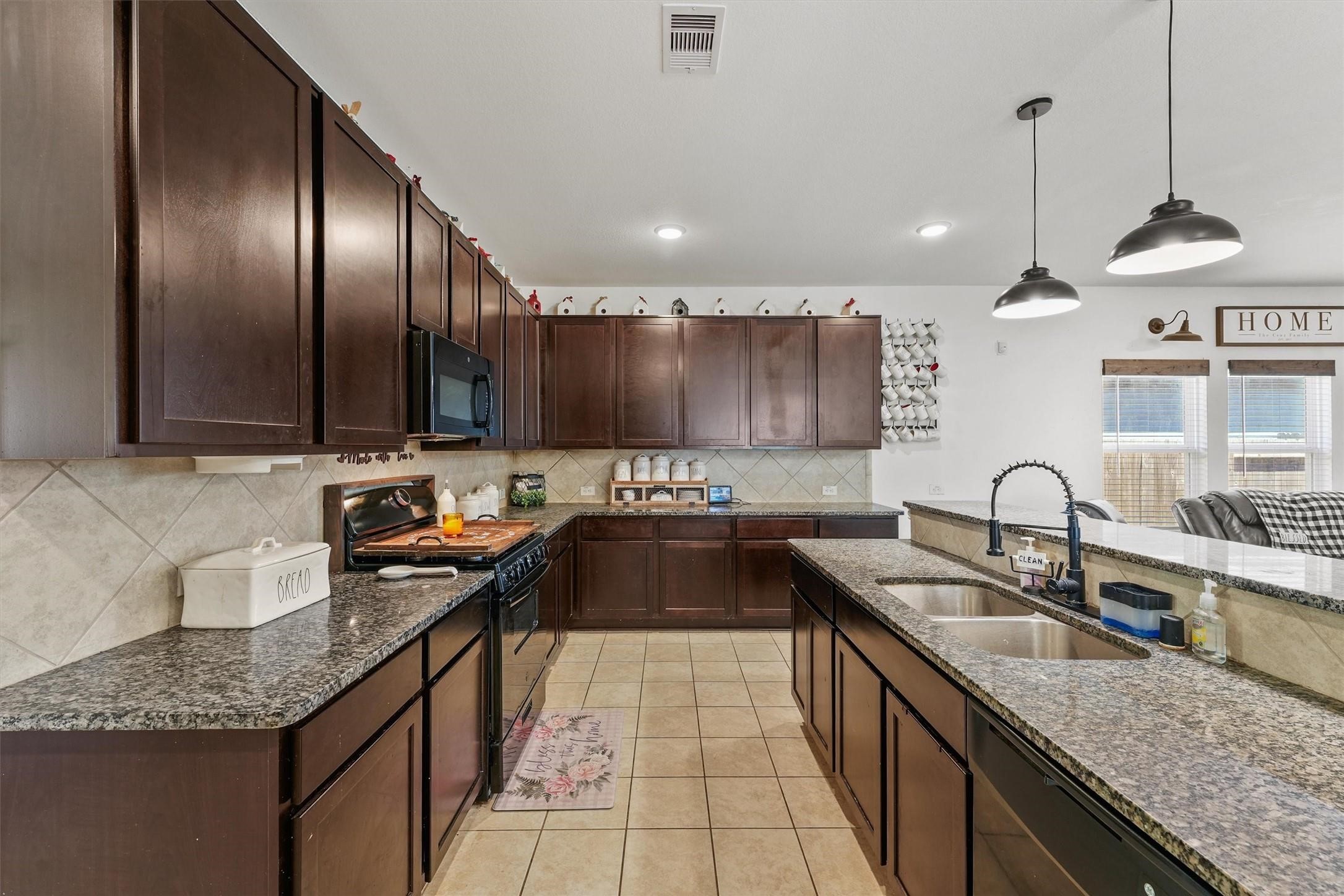 a kitchen with granite countertop stainless steel appliances a sink stove and cabinets