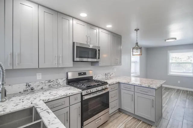 a kitchen with stainless steel appliances granite countertop a stove microwave and sink