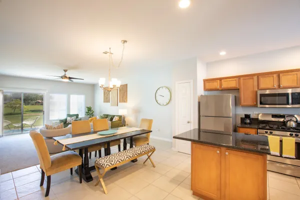 a room with stainless steel appliances a dining table chairs and a kitchen view