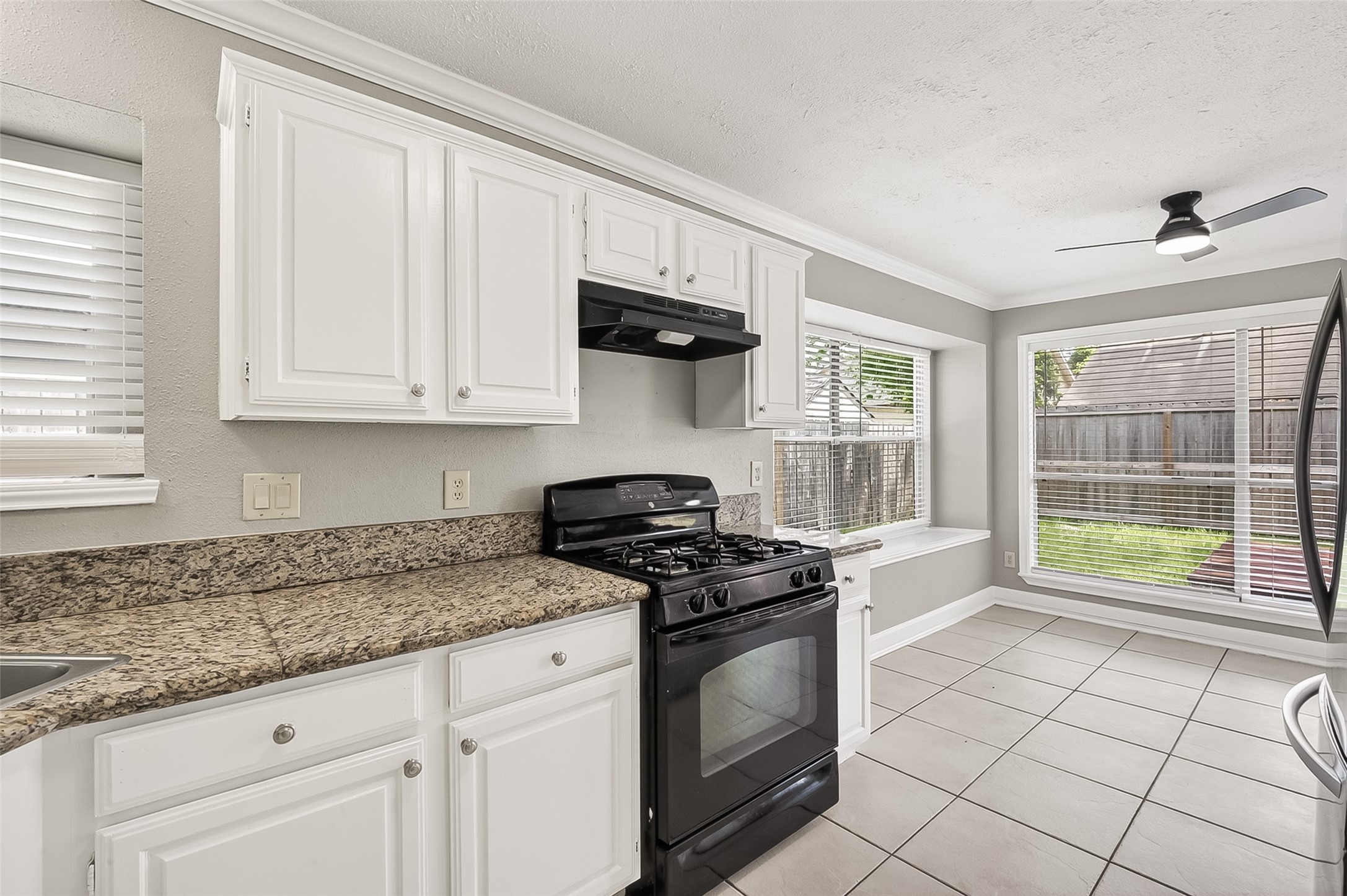12403 Meadow Ridge Drive Stafford, TX 77477 - Photo 14 of 47 a kitchen with granite countertop a stove a sink dishwasher and a microwave oven with white cabinets