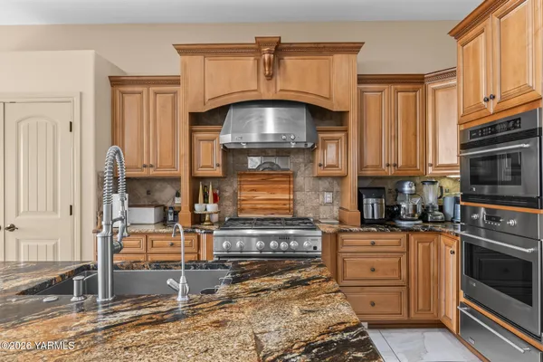 a kitchen with kitchen island granite countertop wooden cabinets and stainless steel appliances