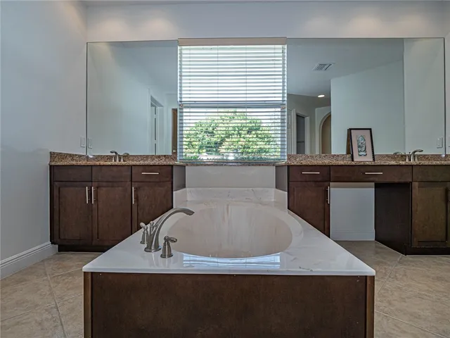 a bathroom with a granite countertop sink a bathtub and window