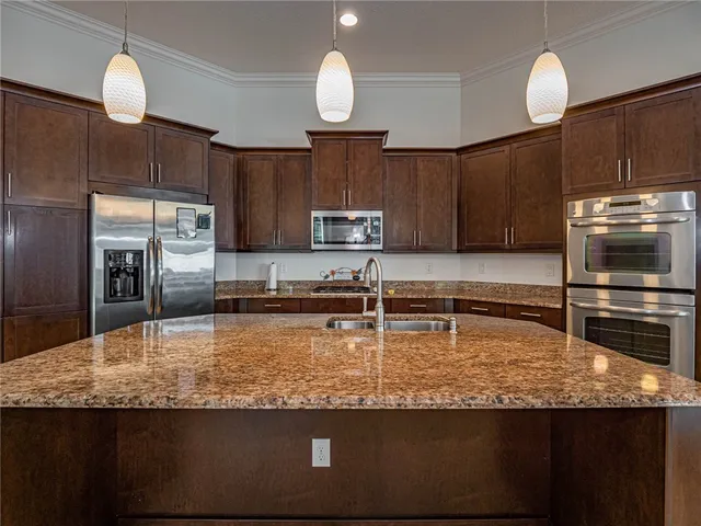 a kitchen with kitchen island granite countertop a sink a counter space appliances and cabinets