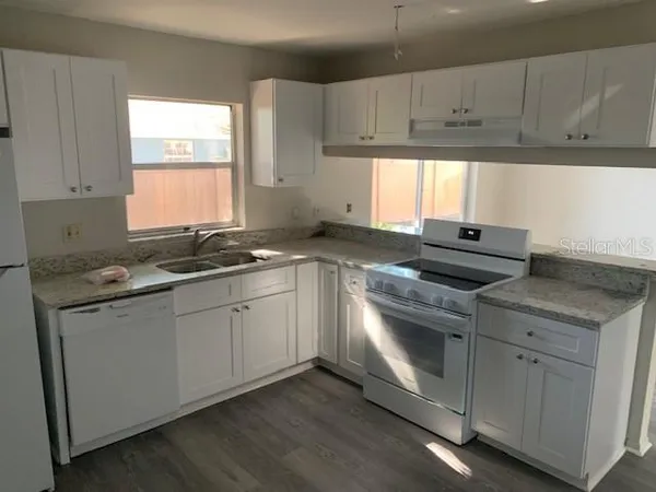 a kitchen with granite countertop a sink cabinets stainless steel appliances and a window