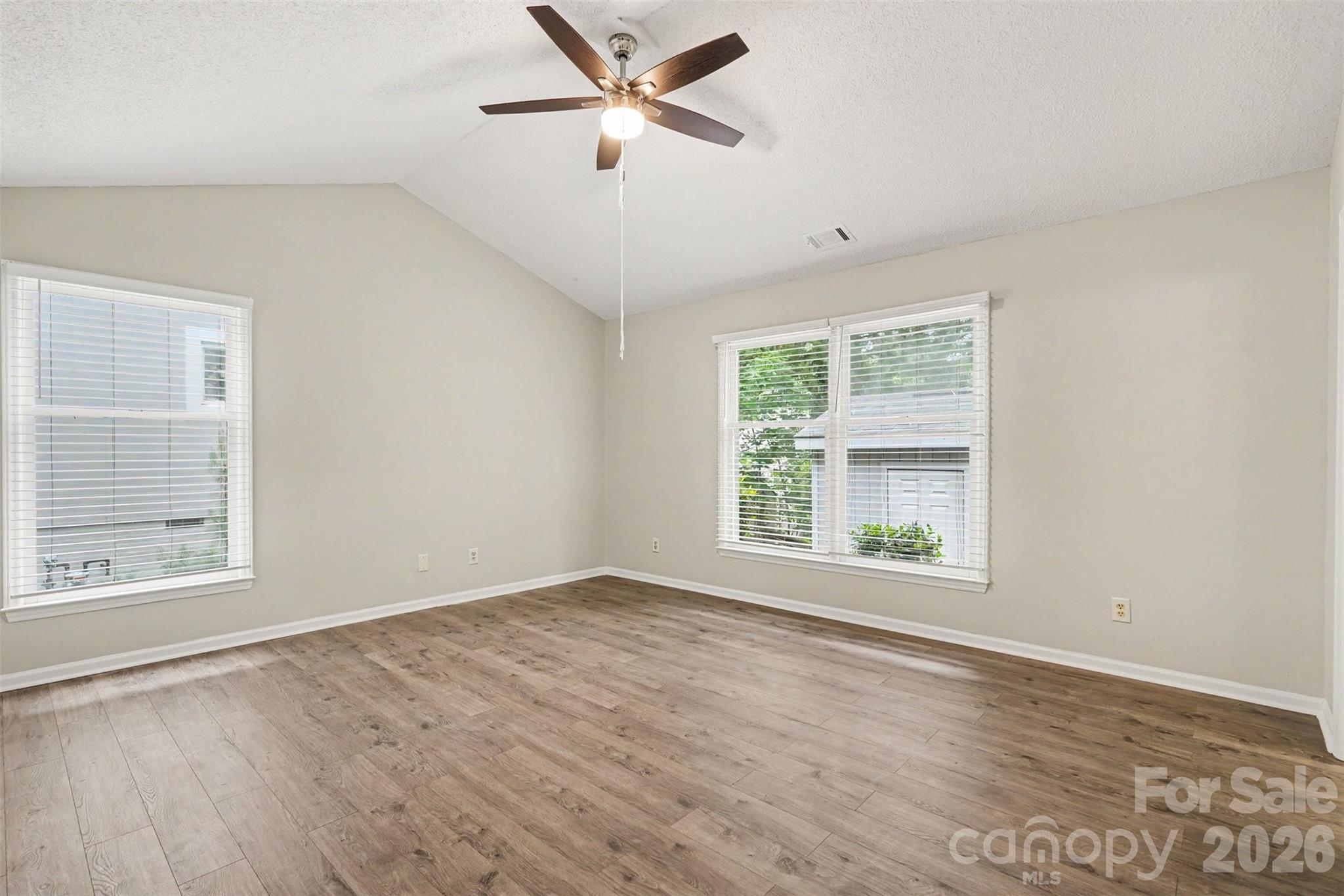 9060 Tulagi Court Tega Cay, SC 29708 - Photo 20 of 29 an empty room with wooden floor ceiling fan and windows