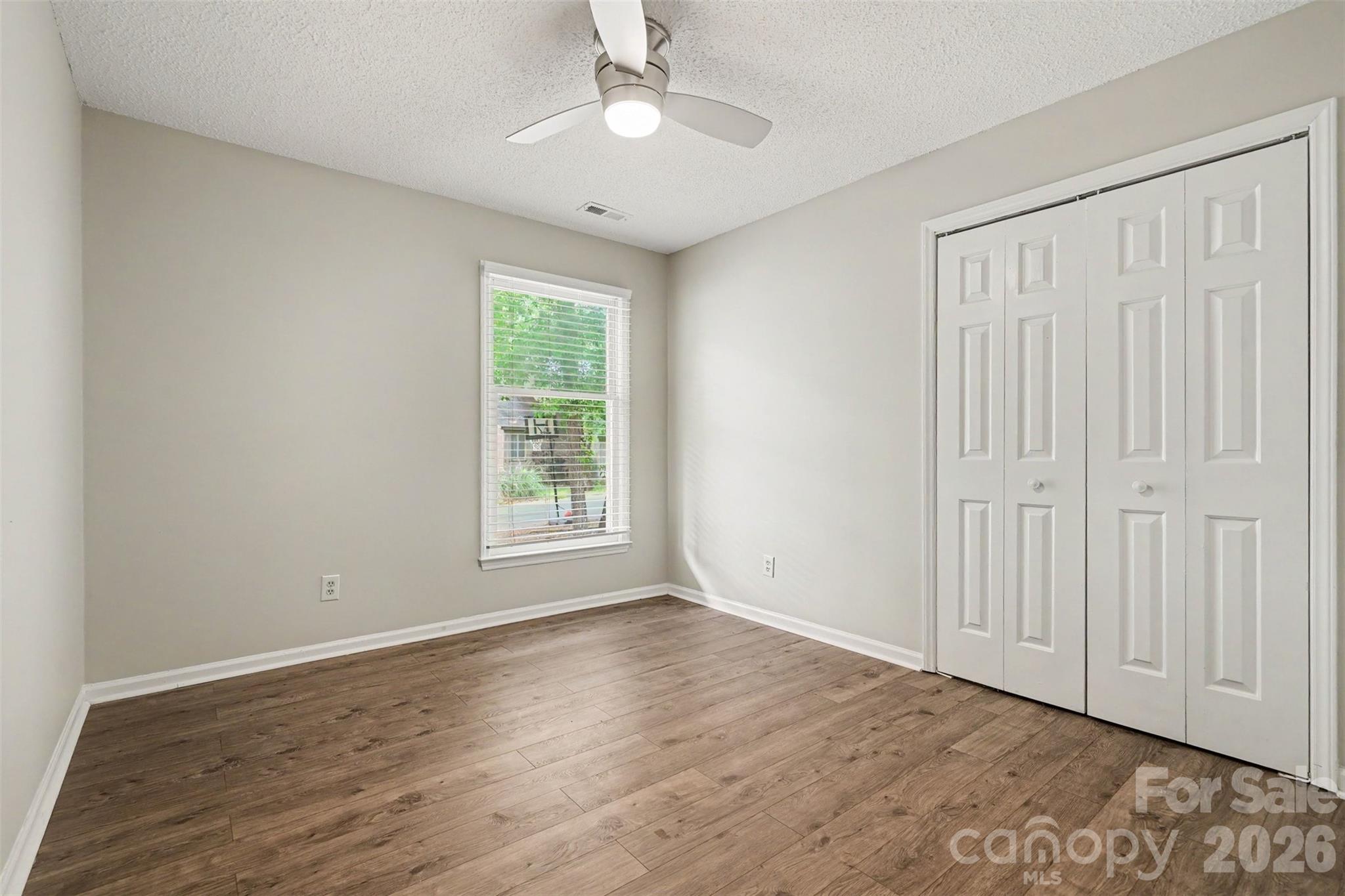 9060 Tulagi Court Tega Cay, SC 29708 - Photo 24 of 29 an empty room with wooden floor chandelier fan and windows