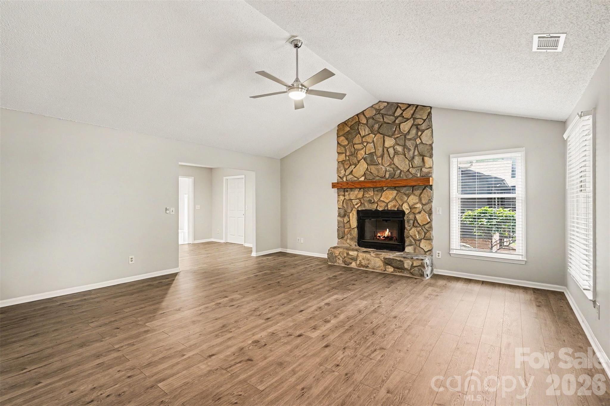 9060 Tulagi Court Tega Cay, SC 29708 - Photo 5 of 29 an empty room with windows fireplace and wooden floor