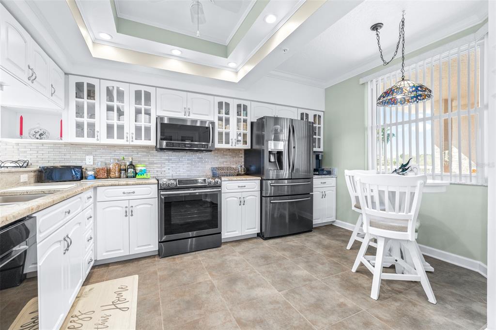6399 Shoreline Drive, Unit 4206 St. Petersburg, FL 33708 - Photo 13 of 40 a kitchen with stainless steel appliances granite countertop a stove top oven a sink dishwasher a dining table and chairs with wooden floor