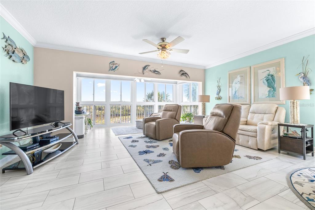 6399 Shoreline Drive, Unit 4206 St. Petersburg, FL 33708 - Photo 5 of 40 a living room with furniture a flat screen tv and a large window