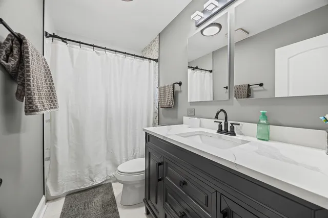 a bathroom with a granite countertop sink a toilet and a mirror