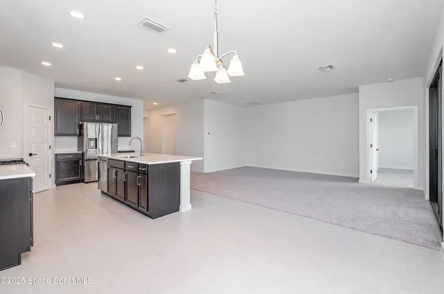 a large kitchen with a large counter top a sink stainless steel appliances and cabinets