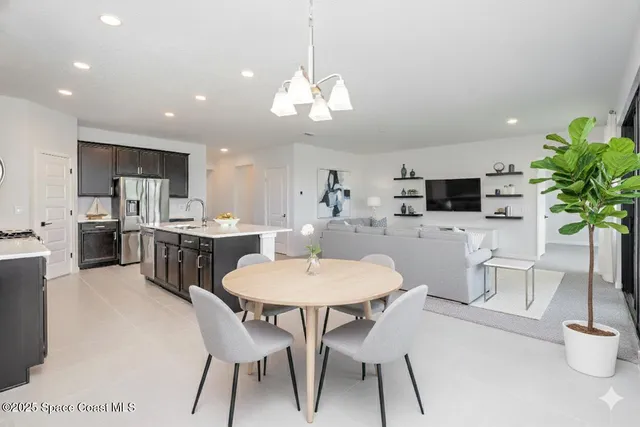 a kitchen with stainless steel appliances kitchen island granite countertop a dining table chairs and white cabinets