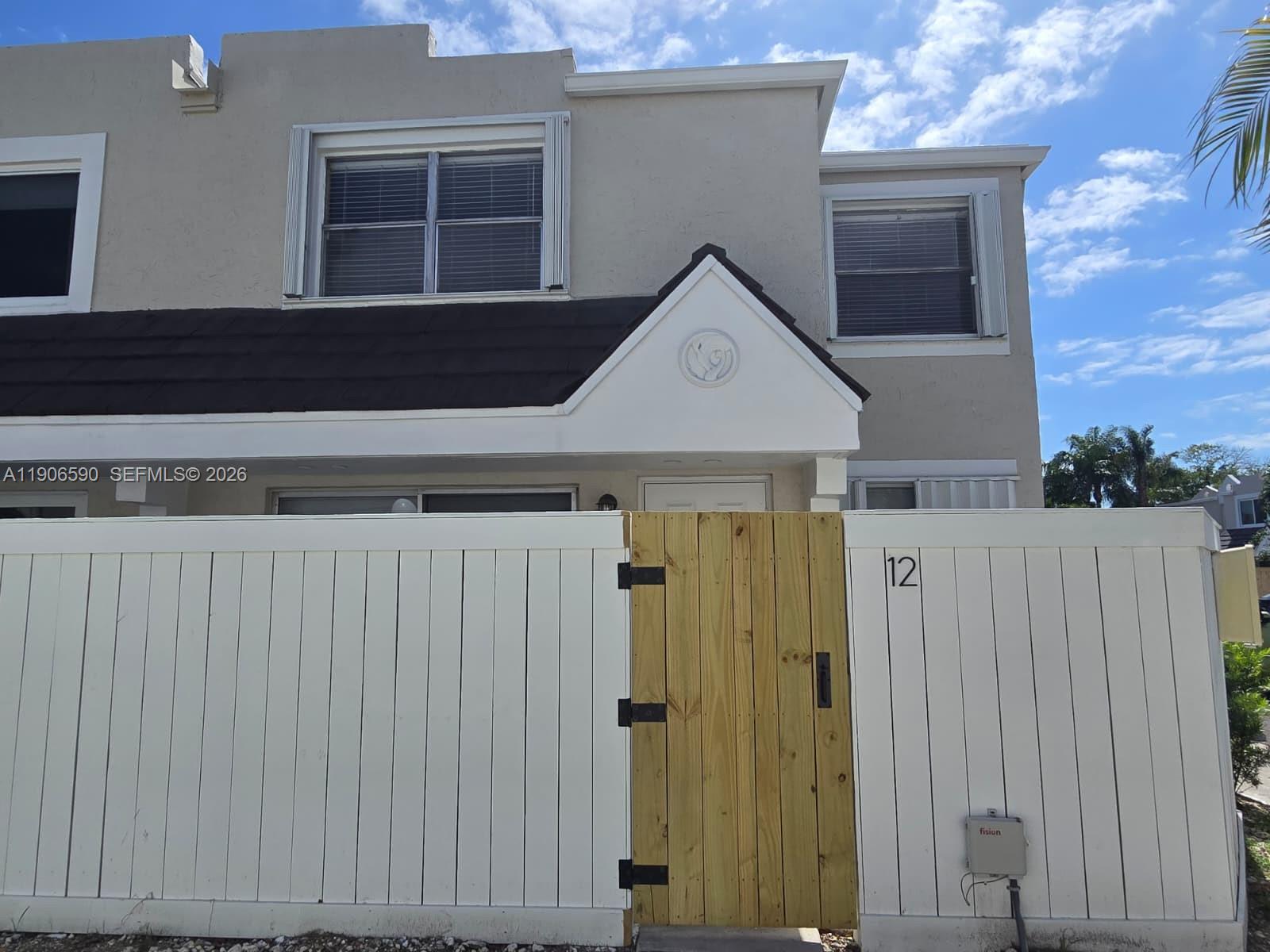 6825 Southwest 45th Lane, Unit 12 Miami, FL 33155 - Photo 1 of 17 a front view of a house with a wooden fence