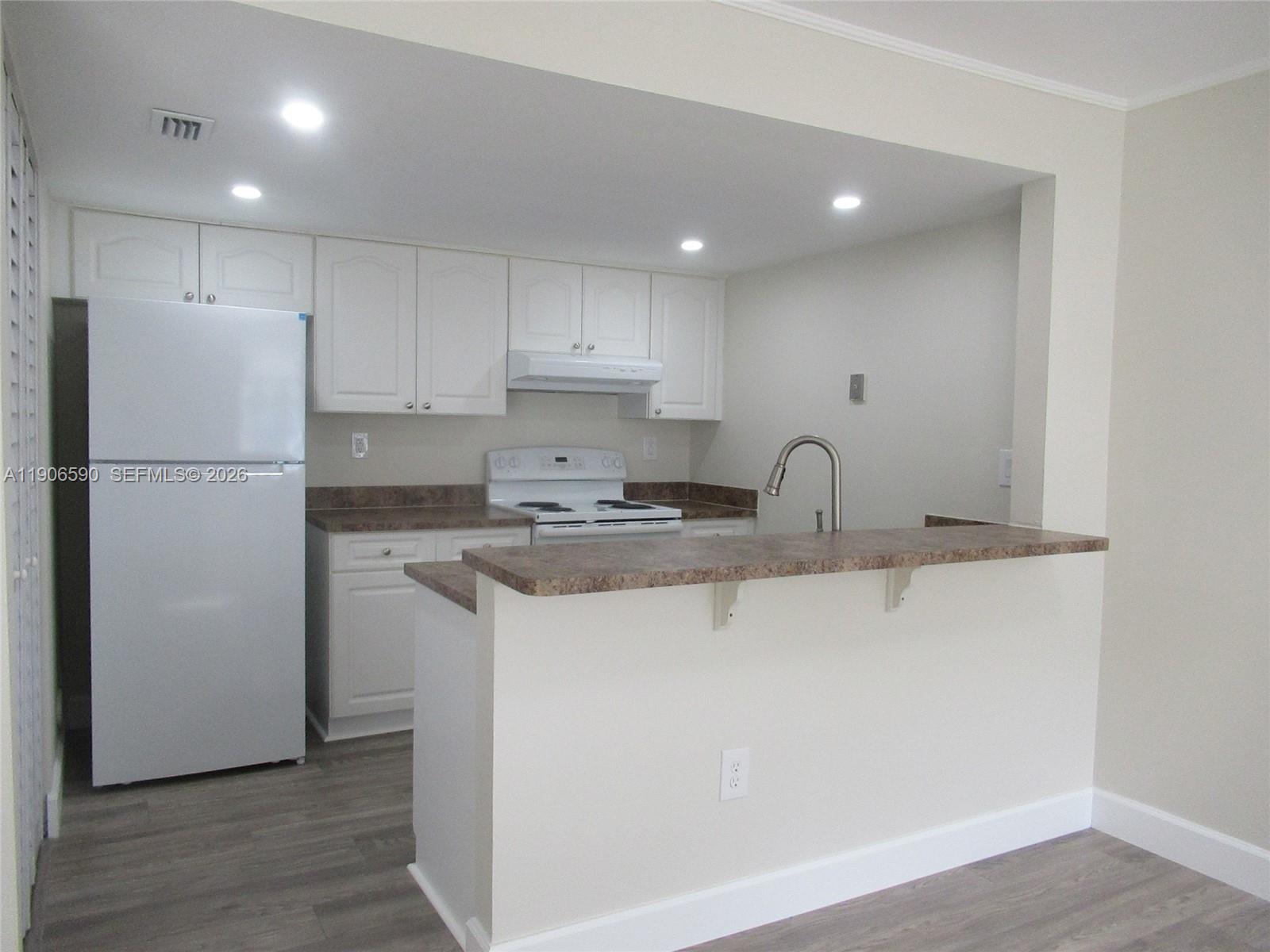 6825 Southwest 45th Lane, Unit 12 Miami, FL 33155 - Photo 5 of 17 a kitchen with a refrigerator a sink and cabinets
