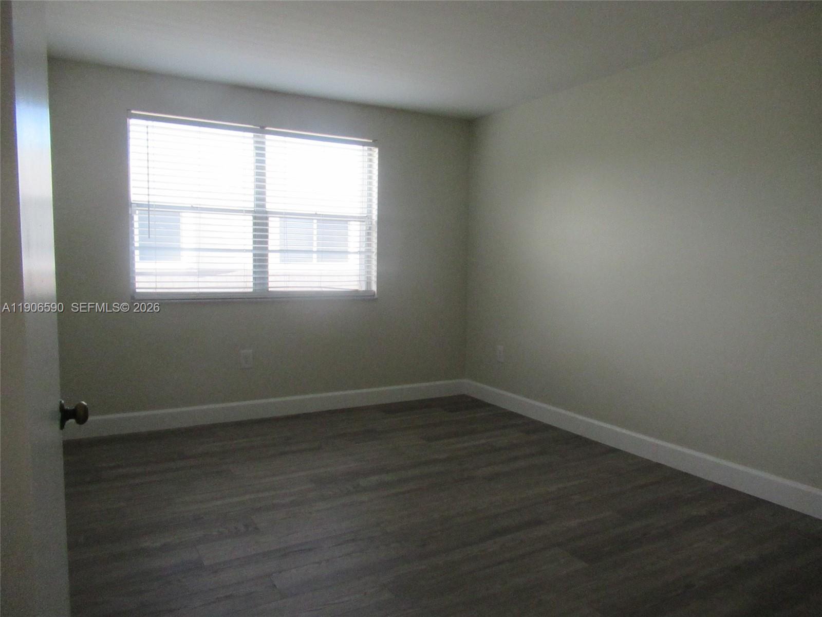 6825 Southwest 45th Lane, Unit 12 Miami, FL 33155 - Photo 10 of 17 an empty room with wooden floor and windows