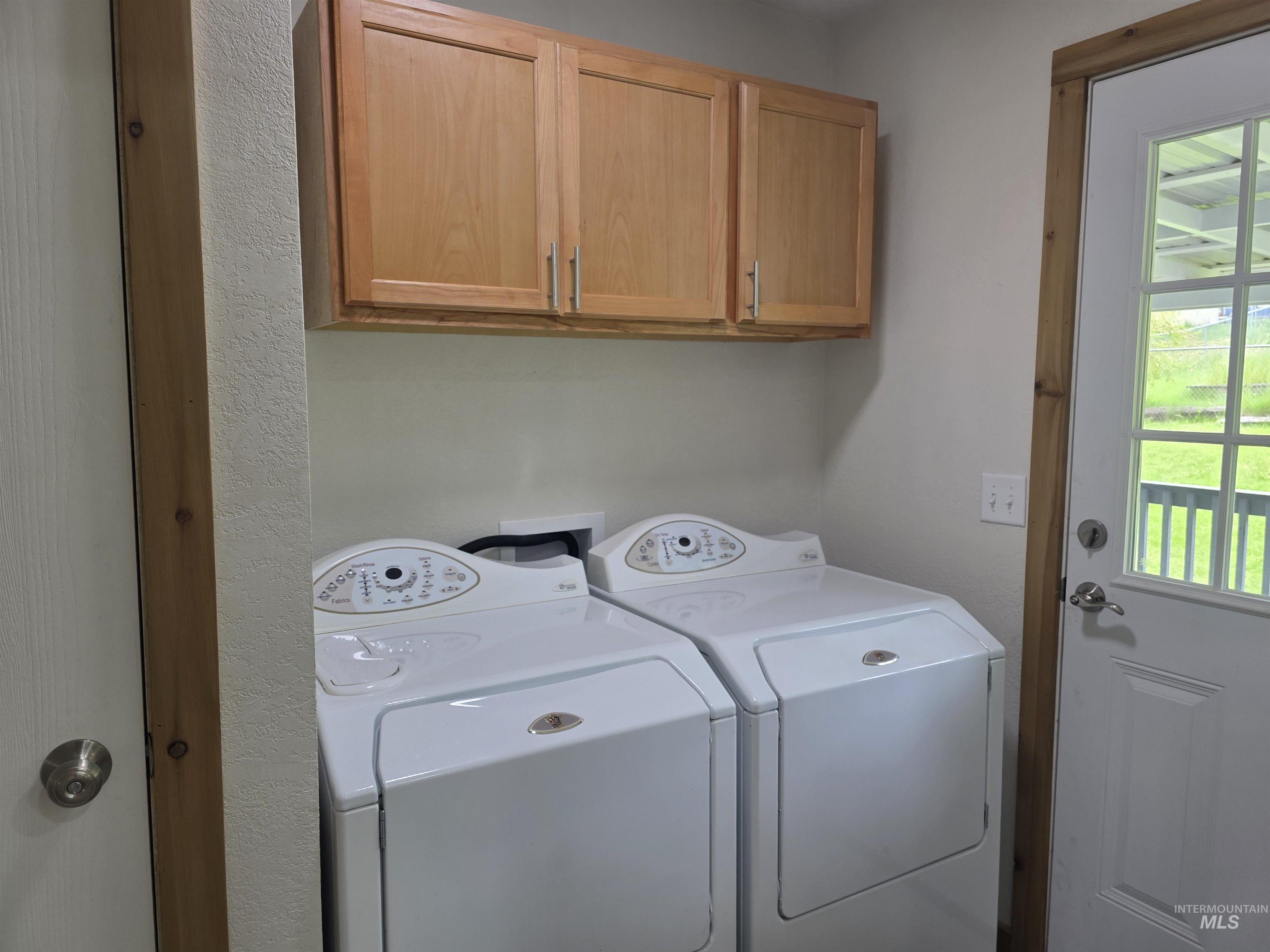 310 Fir Road Kamiah, ID 83536 - Photo 16 of 32 Laundry area featuring wood-finish cabinetry, light neutral wall paint, and a multi-paneled exterior door with a window