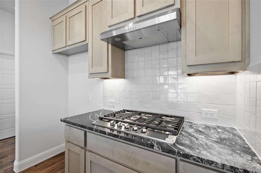 613 Brazos Drive Van Alstyne, TX 75495 - Photo 10 of 29 Kitchen featuring dark stone countertops, tasteful backsplash, under cabinet range hood, and light brown cabinets