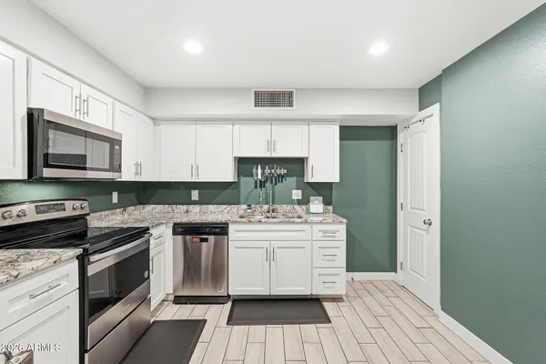 a kitchen with stainless steel appliances a stove refrigerator and cabinets