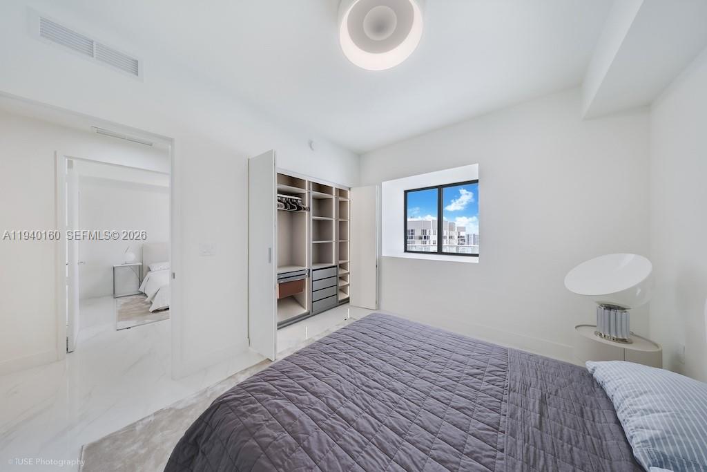 700 Northeast 24th Street, Unit 1403 Miami, FL 33137 - Photo 14 of 16 a bedroom with a bed and a chair