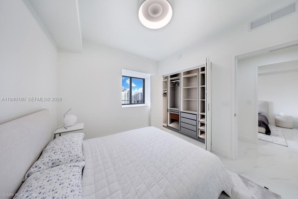 700 Northeast 24th Street, Unit 1403 Miami, FL 33137 - Photo 16 of 16 a bedroom with a bed and a chandelier