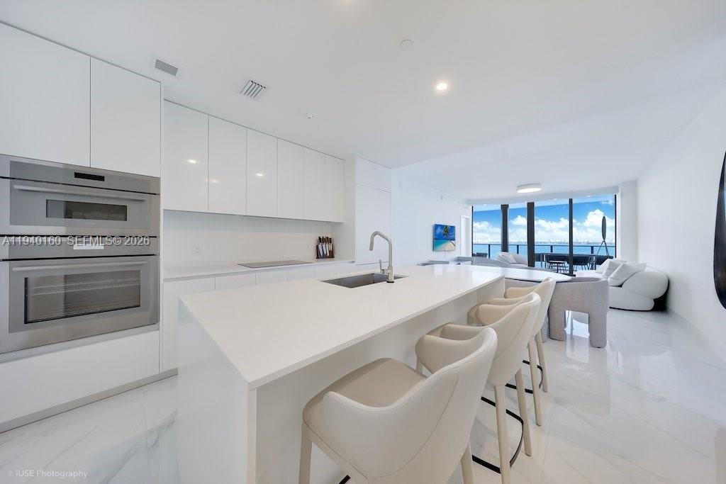 700 Northeast 24th Street, Unit 1403 Miami, FL 33137 - Photo 3 of 16 a kitchen with a sink a stove and chairs
