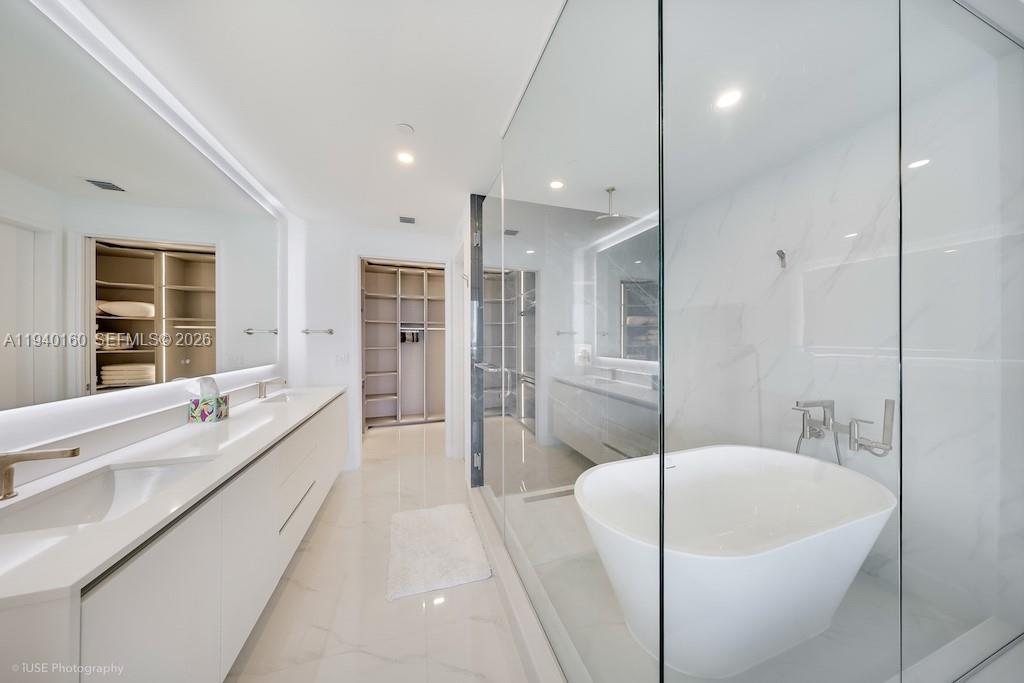 700 Northeast 24th Street, Unit 1403 Miami, FL 33137 - Photo 9 of 16 a large white bathroom with a large tub a sink a vanity and a shower