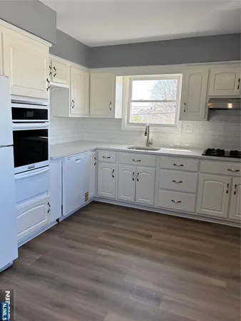 a kitchen with granite countertop white cabinets stainless steel appliances and a window