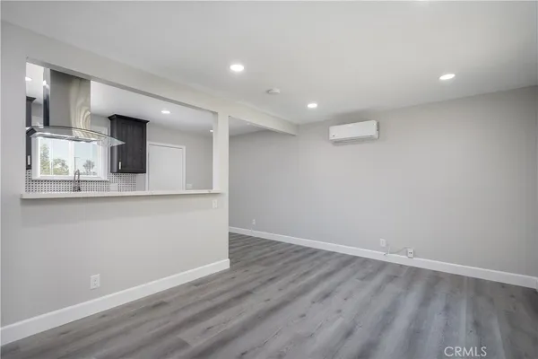 an empty room with wooden floor and a kitchen