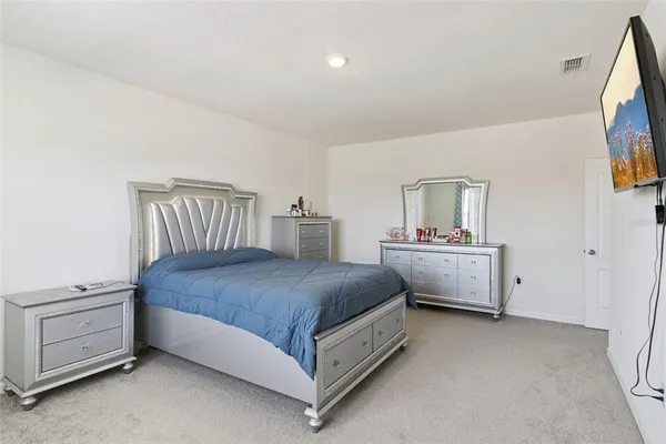 a bedroom with a bed and a flat tv screen on dresser