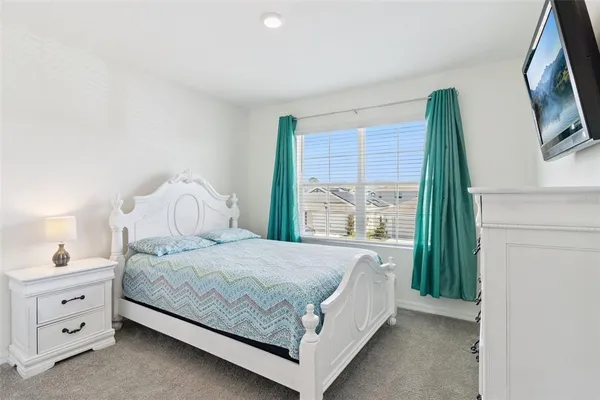a bedroom with a bed and a flat tv screen on dresser