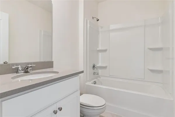 a bathroom with a granite countertop bathtub shower sink vanity mirror and toilet
