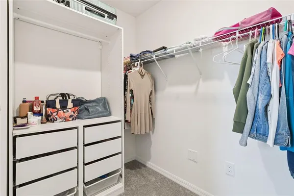 a view of walk in closet with clothes and shoes