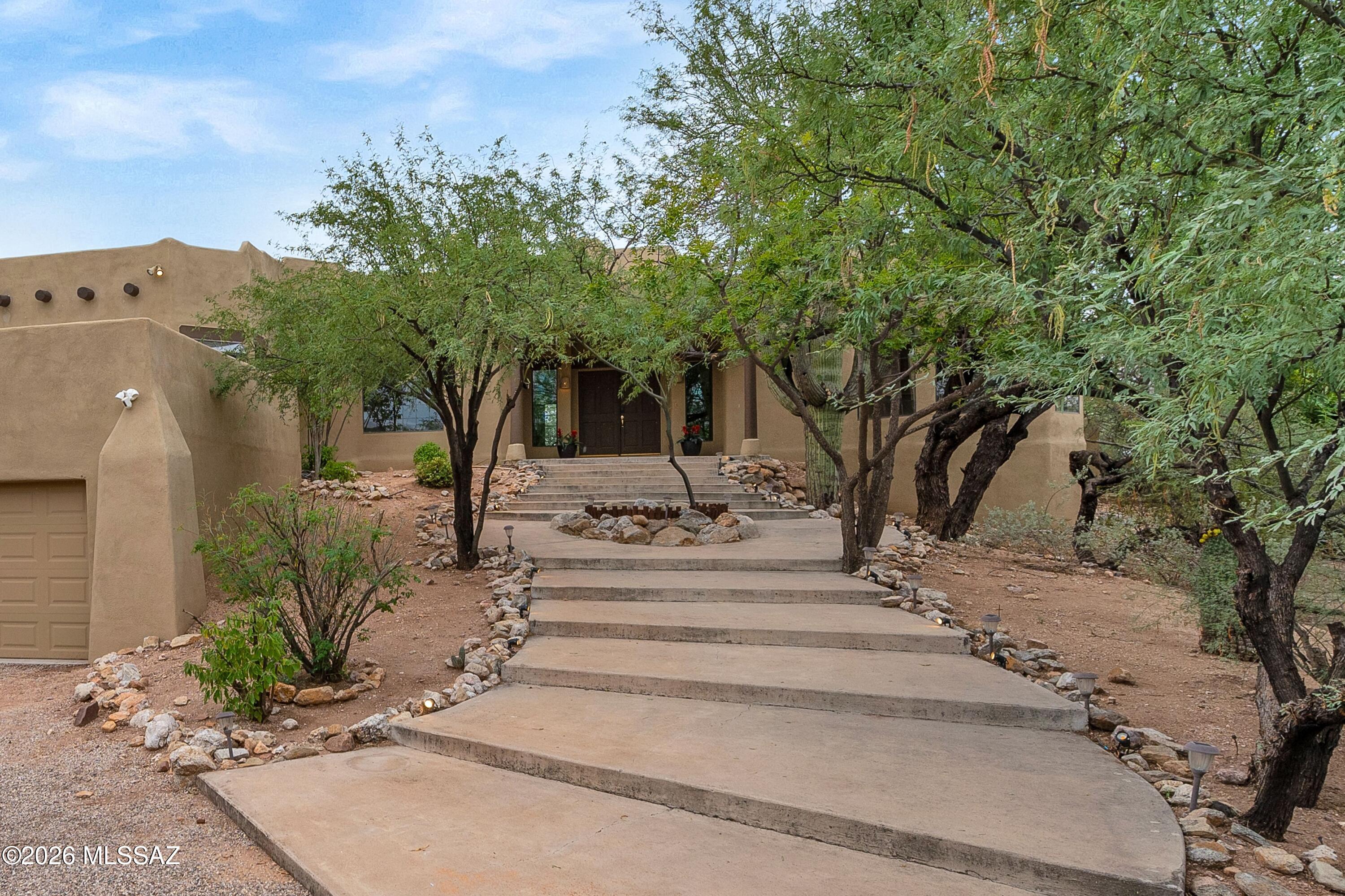 12160 East Tanque Verde Road Tucson, AZ 85749 - Photo 2 of 53 Concrete steps bordered by river rock and mesquite trees lead up to the covered entry.