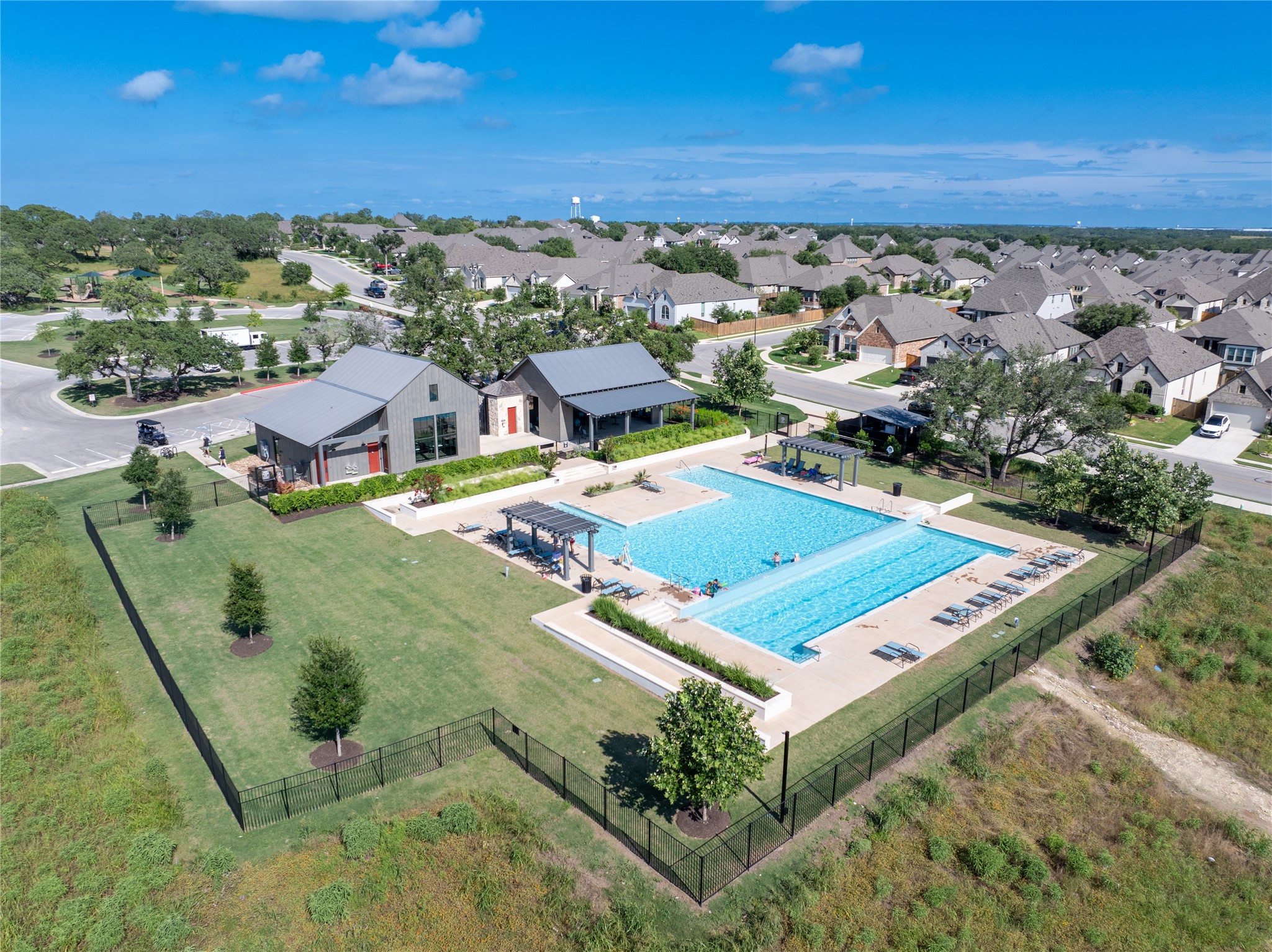 294 Kimble Creek Loop Kyle, TX 78640 - Photo 32 of 40 An aerial perspective reveals a vibrant community hub, featuring a refreshing swimming pool and inviting gathering spaces.
