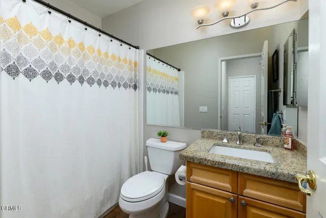 a bathroom with a granite countertop sink mirror vanity and toilet