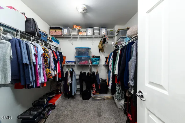a view of walk in closet with clothes and shoes