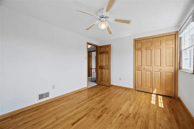 an empty room with wooden floor fan and windows