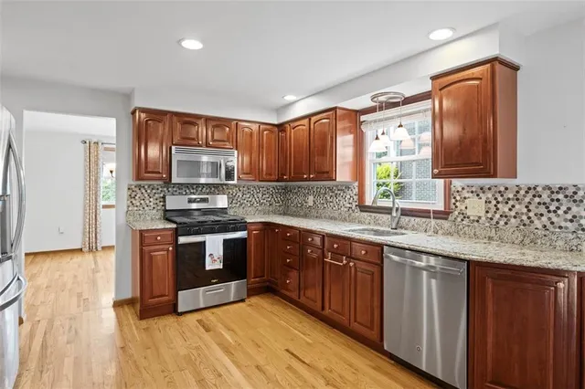 a kitchen with stainless steel appliances granite countertop wooden cabinets a sink and dishwasher with wooden floor