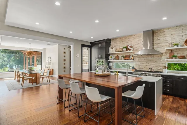 a dining room with stainless steel appliances granite countertop a stove a table and chairs with wooden floor